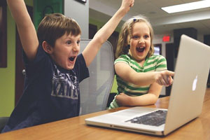 パソコン画面を見て喜ぶ子供たちの画像
